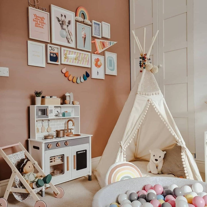 Children's playroom with a teepee, toy kitchen, and colorful balloons.